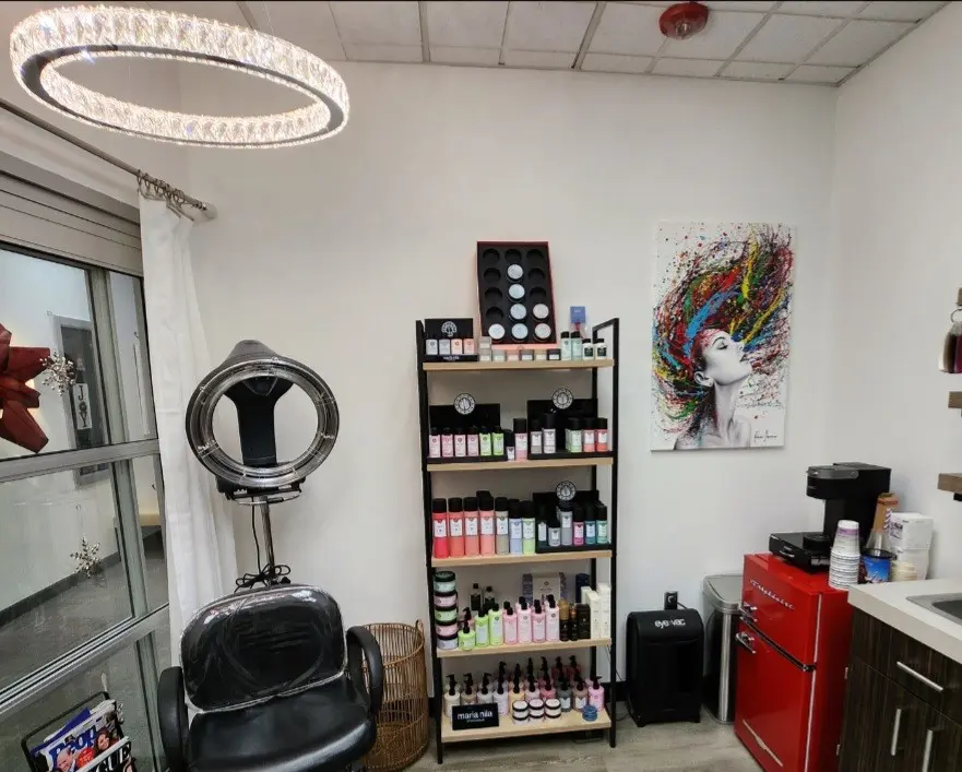 A hair salon with a black chair and a white wall