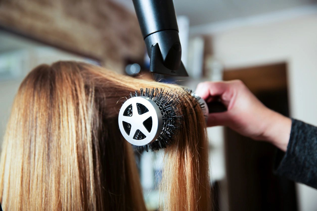 A person blow drying their hair with a brush.