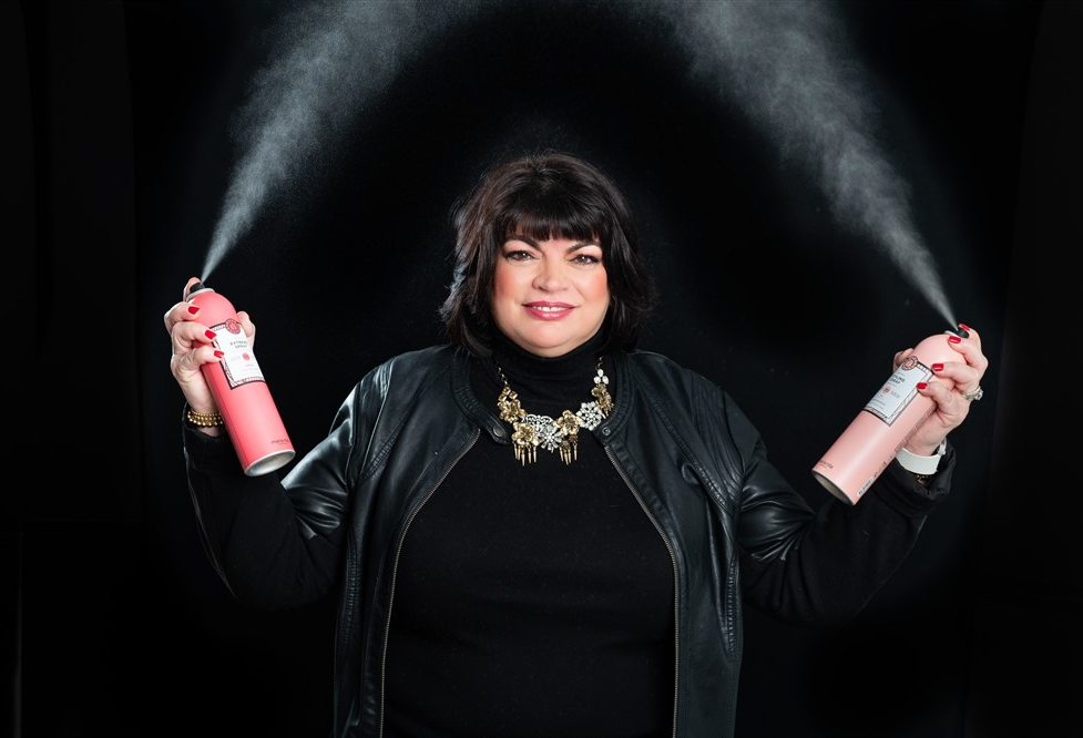 A woman holding two spray bottles in front of her face.